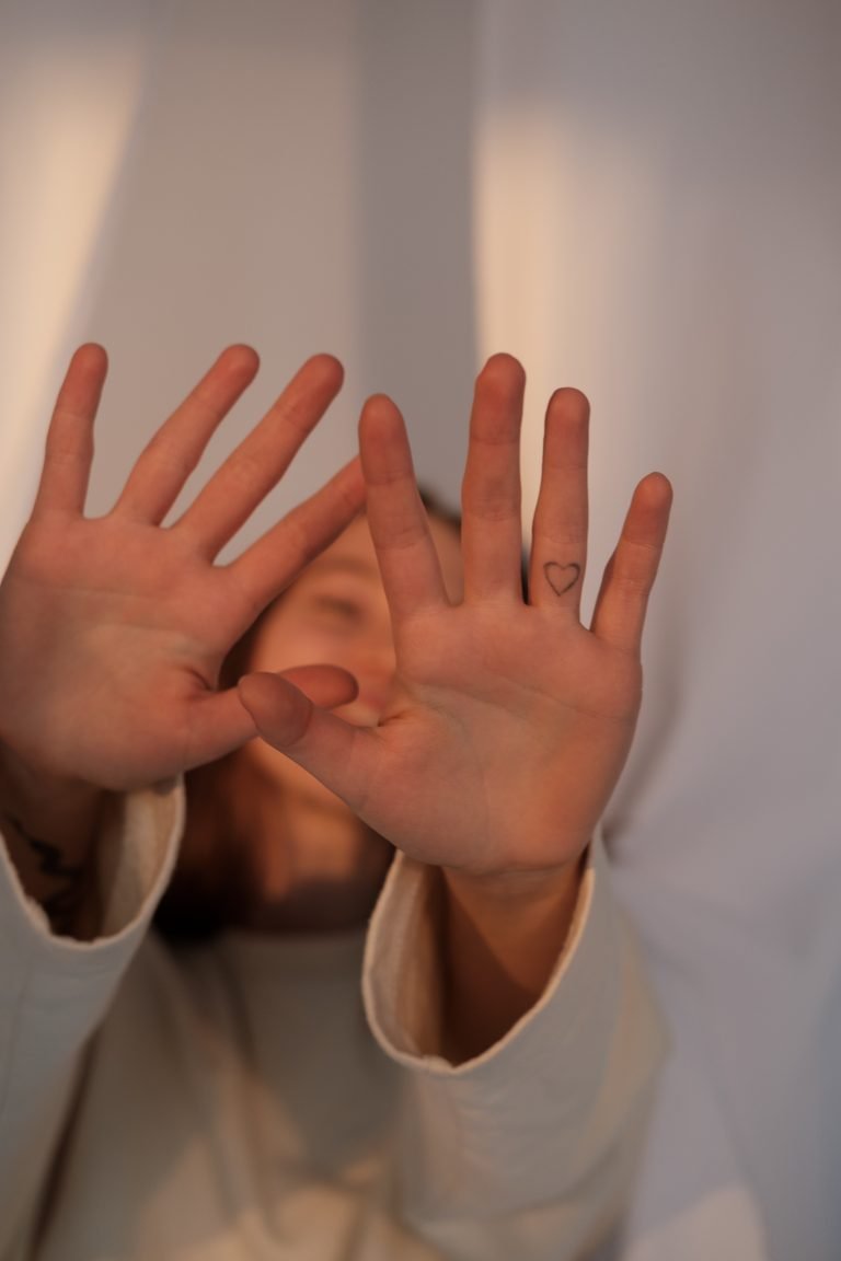 Girl dressed in white hiding behind her hands not wanting to show her emotions